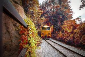 tren de procesión locomotoras eléctricas diesel que se mueven en la montaña en la curva y navegan a través del helicóptero ferroviario con hermosas vistas al bosque otoñal foto