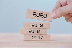 Hand holding chooses wooden block cubes with word 2020 , new year concept photo