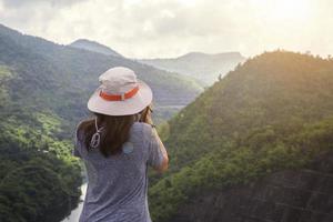 mujer viajera feliz relajándose con mochila y mirando increíbles montañas y bosques en el día de verano, vacaciones de verano al aire libre viaje de vacaciones foto