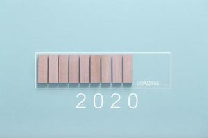 cargando el concepto de año nuevo 2020, mostrando la barra de carga con cubo de madera sobre fondo azul foto