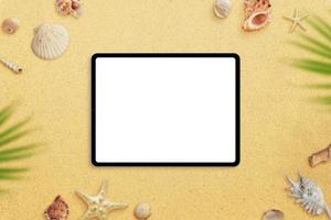 Tablet mockup on beach sand surrounded by sea shells and palm leaves. Top view, flat lay photo