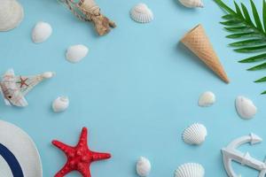 Summer travel composition with copy space in the middle for promo text. Shells, hat, starfish, ice cream cone, anchor, palm leaves on blue surface. Copy space in the middle for promotion photo