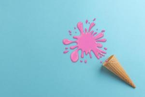 Dropped ice cream on cyan surface concept. Spilled pink cream. Top view, flat lay composition photo