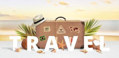 Travel text front of retro suitcase with travel stickers on beach surrounded by palm leaves, coconuts and shells photo