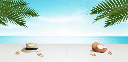 Travel background with copy space in the middle. Desk with traveler hat, coconuts and shells with palm leaves above. photo