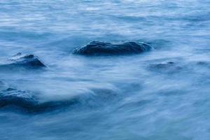 Long exposure smooth ocean wave moving into rock. photo