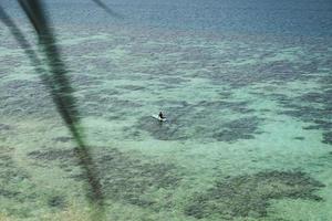 mujer relajándose en stand up paddle board en el mar azul. foto