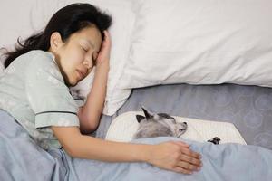 Woman sleeping and hugging dog lying on bed at bedroom. photo