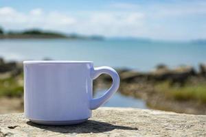 Empty white cup on blurred beach background photo