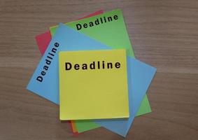 Deadline text on colorful notepad on wooden desk. Business concept photo