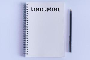 Latest updates text on notepad on white background. News concept photo