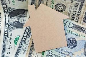 Brown paper house model with dollar banknotes on dark wooden table photo