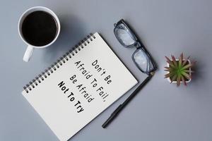 Motivational quote on notepad with cup of coffee and reading glasses photo