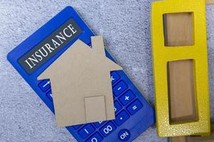 Insurance text on calculator with paper house model and window frame on a desk photo