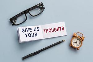 Text on notepad with reading glasses, pen and alarm clock on blue background. photo