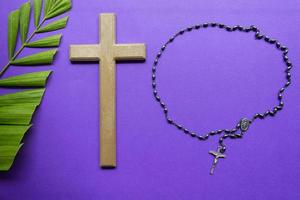 Cross and palm leaves on purple background. Lent season concept. photo