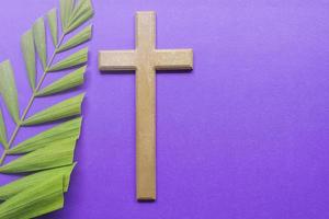 Cross and palm leaves on purple background. Lent season concept. photo