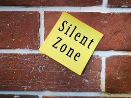 Text on sticky yellow note on brick wall. Silent zone photo