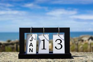 13 de enero texto de fecha de calendario en marco de madera con fondo borroso del océano foto