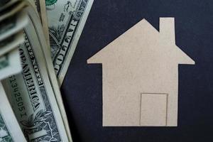 Brown paper house model with dollar banknotes on dark wooden table photo