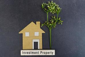 Investment property text on wooden block with house model on dark wooden photo