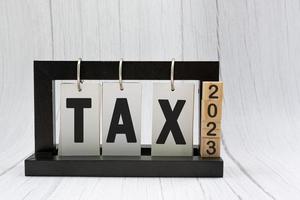 Tax text on paper stand black frame with wooden blocks on white background photo