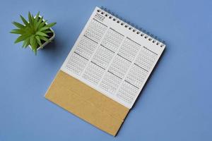 2022 white calendar with potted plant on blue background. Flat lay photo