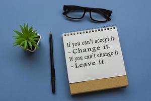 Motivational quote on notepad with potted plant, glasses and a pen photo