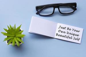 Motivational quote on notepad with reading glasses and potted plant photo