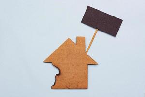 Burned paper house model on blue background. Home insurance concept photo