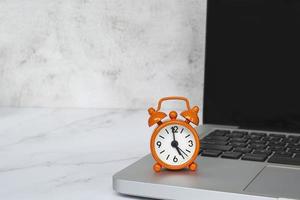 Alarm clock isolated on laptop or notebook. The clock set at 5 o'clock. photo