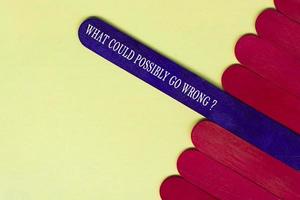 What could possibly go wrong question text on purple color wooden stick. photo