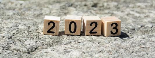 2023 number on wooden cube block on stone with blurred background of ocean