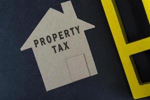 Property tax text on brown paper house model on dark wooden table photo