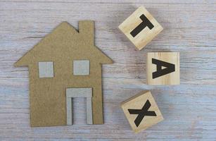 Paper House Model Near Wooden Blocks With Tax Text On Wooden Background photo