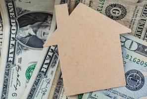 Brown paper house model with dollar banknotes on dark wooden table photo