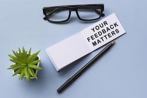 Text on notepad with reading glasses and potted plant on blue background photo