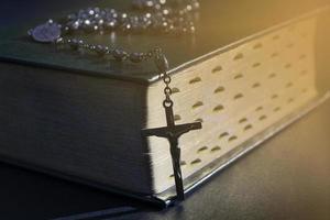 The cross over bible on wooden table with window light, vintage tone.
