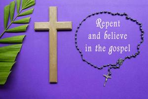 Cross and palm leaves with text on purple background. Holy week concept. photo