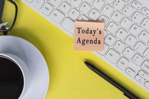 Today's agenda text on sticky note with computer keyboard on yellow background. photo