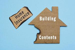 Text on burned paper house model on blue background. Home insurance concept. photo
