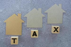 Paper House Model And Tax Text On Wooden Block. Directly above. Flat lay photo