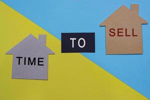 Time to sell text on paper house model with colored paper background photo