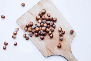 Top view of group of hazelnuts on a wooden board. White background photo
