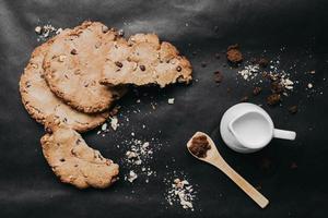 Top view of homemade chocolate cookies, dark brown sugar and milk on dark background. Food styling. photo