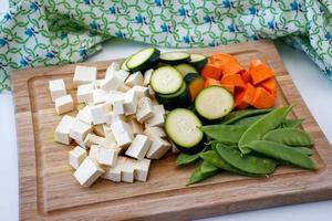 verduras y tofu en una tabla de cutiing foto