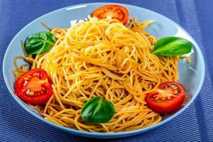 Spaghetti with tomatoes on a blue background