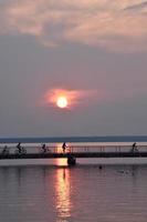 the setting sun creates silhouettes of cyclists riding over a bridge