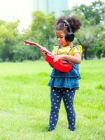 The girl stands on the grass, wears headphones and is learning to play ukulele strings photo