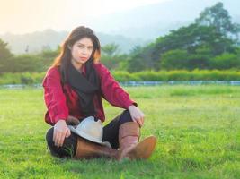 A beautiful western cowgirl sitting on a meadow on a farm after hard work photo